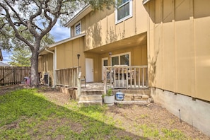 A two-story house with a front porch, a tree, and a small garden area.