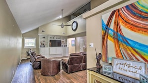 A spacious living room with a ceiling fan, leather sofas, a dining area with a black countertop, and a colorful abstract painting. - Family Retreat ~ 1 Mi to Hill Country Mile! (Boerne)