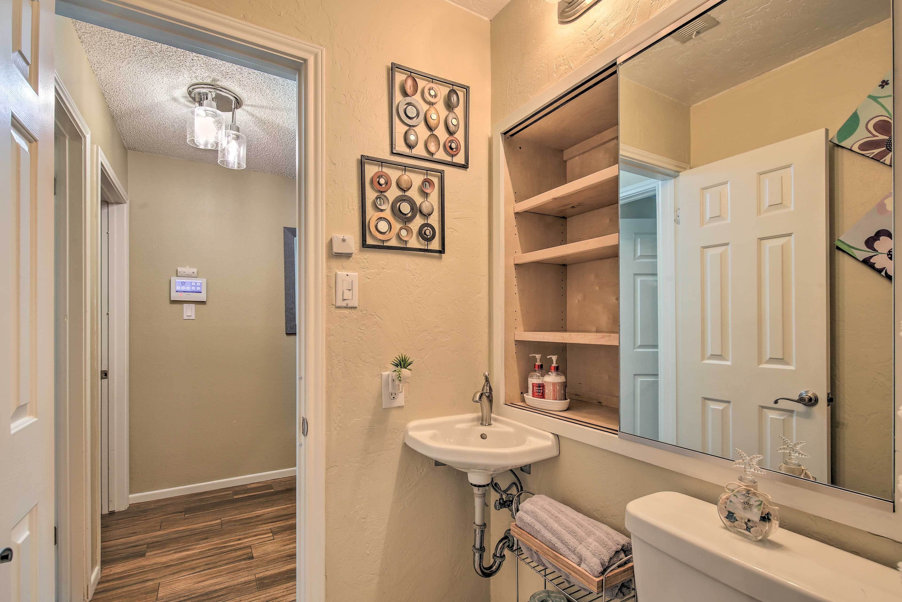 A bathroom with a sink, mirror, and decorative plates on the wall.