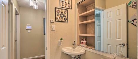 A bathroom with a sink, mirror, and decorative plates on the wall.