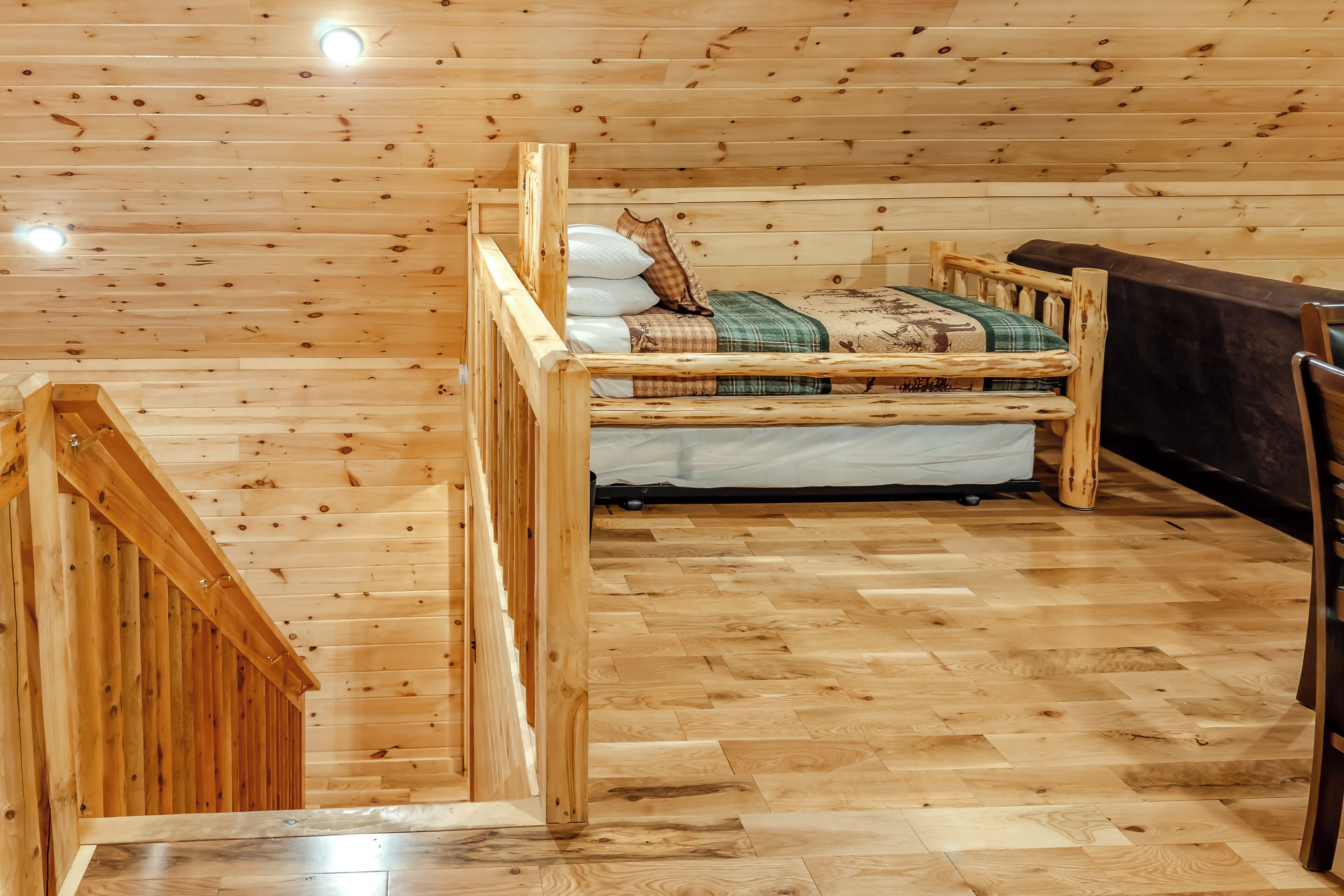 Ein Holzblockhaus-Innenraum mit einem Bett, einem Sessel und einer Treppe.
