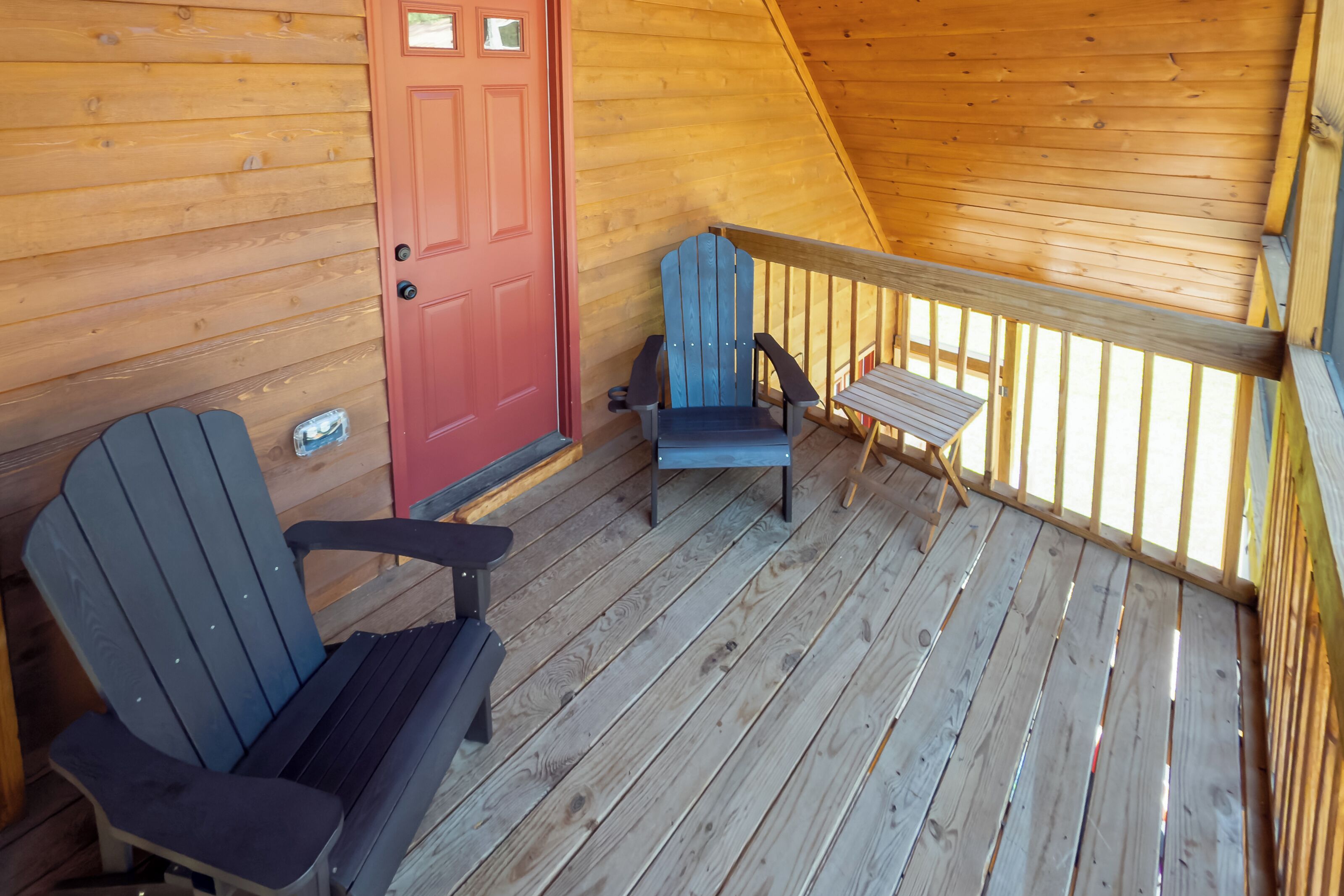 Un patio in legno con due poltrone Adirondack e un tavolino.