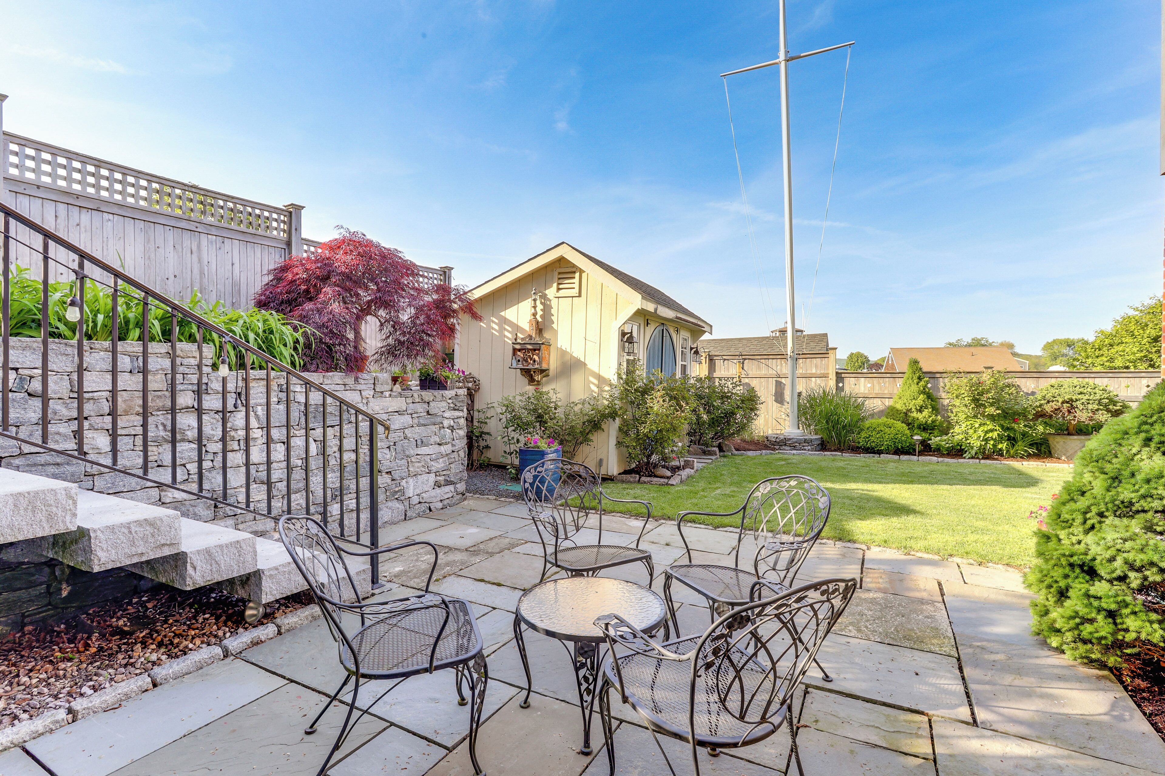 A patio area with outdoor furniture, a stone staircase, and a small building with a window.
