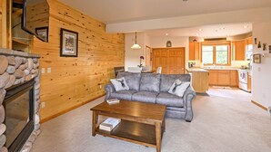 A cozy living room with a stone fireplace, a gray sofa with decorative pillows, and a wooden coffee table. - 7 Mi to National Park: Grand Lake Condo w/ Deck! (Grand Lake)