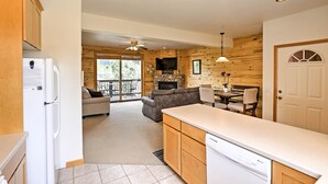 A modern kitchen with wooden cabinets, a dishwasher, and a dining area with a table and chairs. - 7 Mi to National Park: Grand Lake Condo w/ Deck! (Grand Lake)