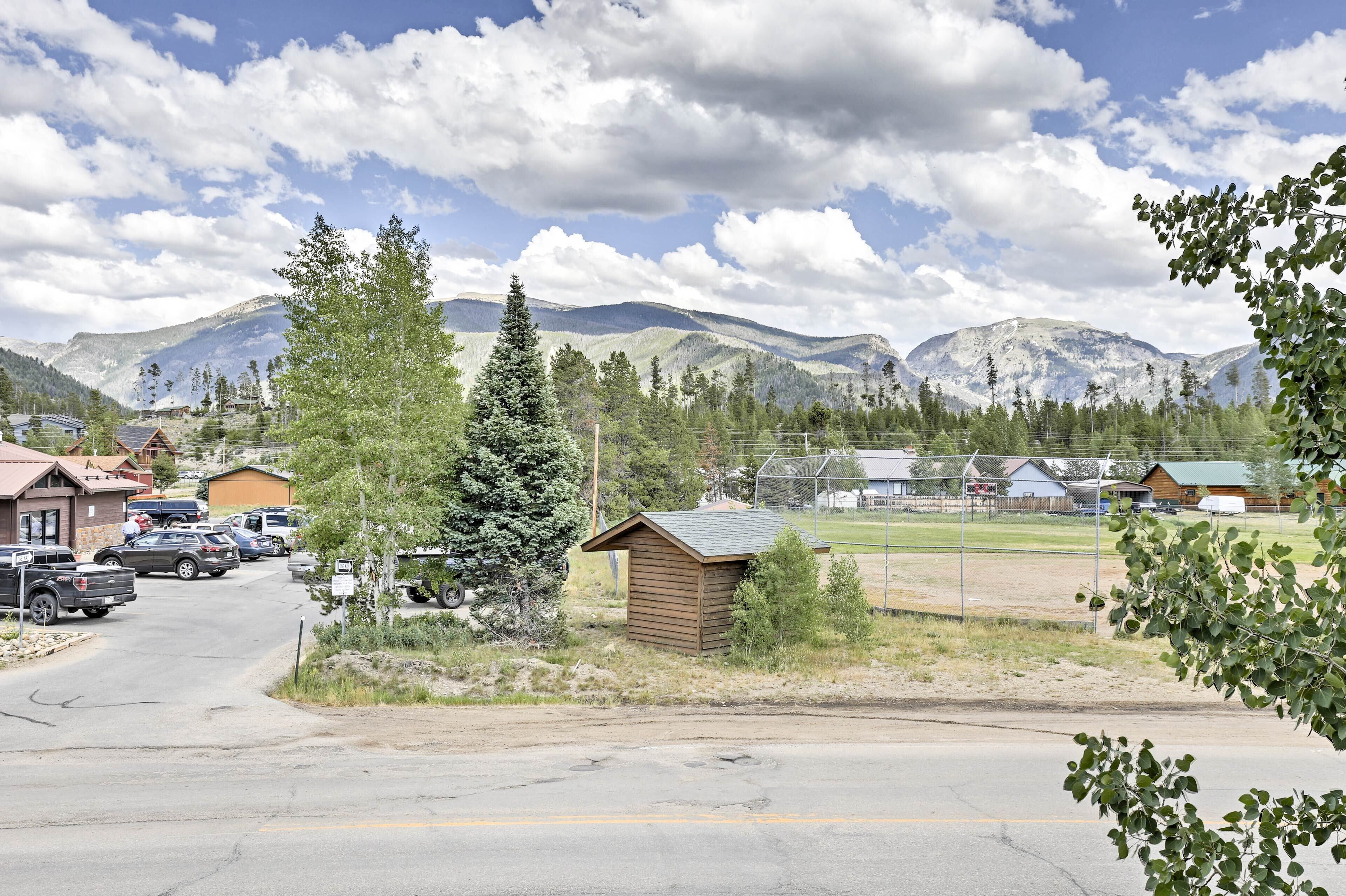 Un petit chalet accessible par un chemin de terre, entouré de montagnes et d’arbres.
