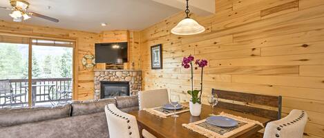 Un intérieur en bois avec une table à manger dressée pour quatre personnes, un canapé et une cheminée.