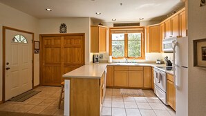 A kitchen with wooden cabinets, a central island, a built-in oven, and a refrigerator. - 7 Mi to National Park: Grand Lake Condo w/ Deck! (Grand Lake)