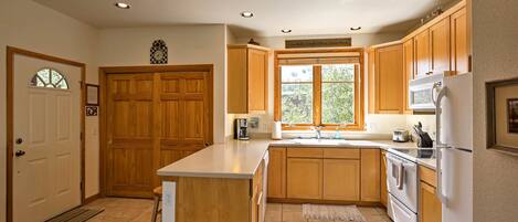 Una cocina con armarios de madera, una isla central, horno empotrado y refrigerador.