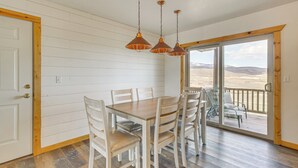 Een eetruimte met een houten tafel en stoelen, een schuifdeur naar een terras met uitzicht op de woestijn.