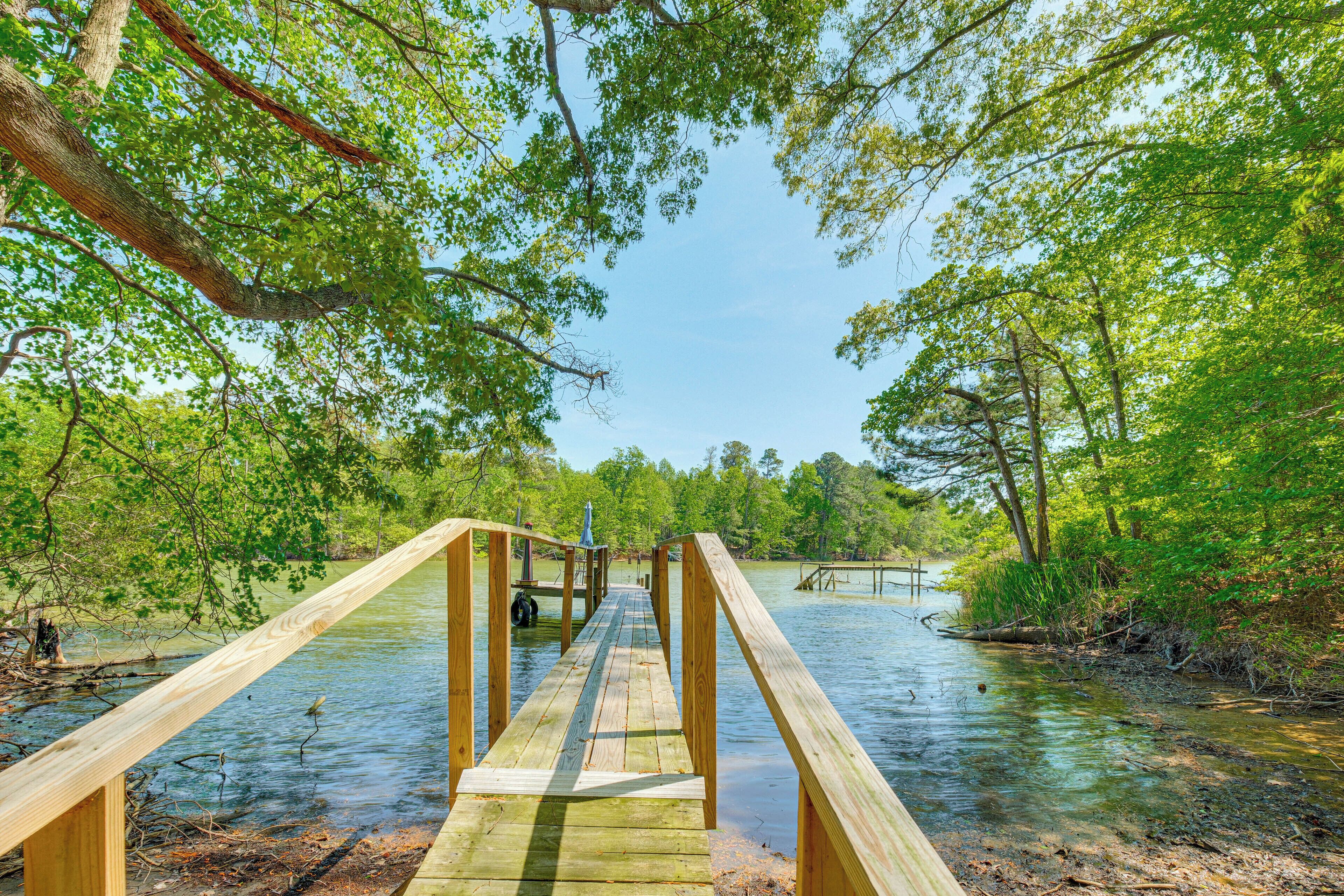 A wooden bridge over a calm body of water surrounded by lush greenery.