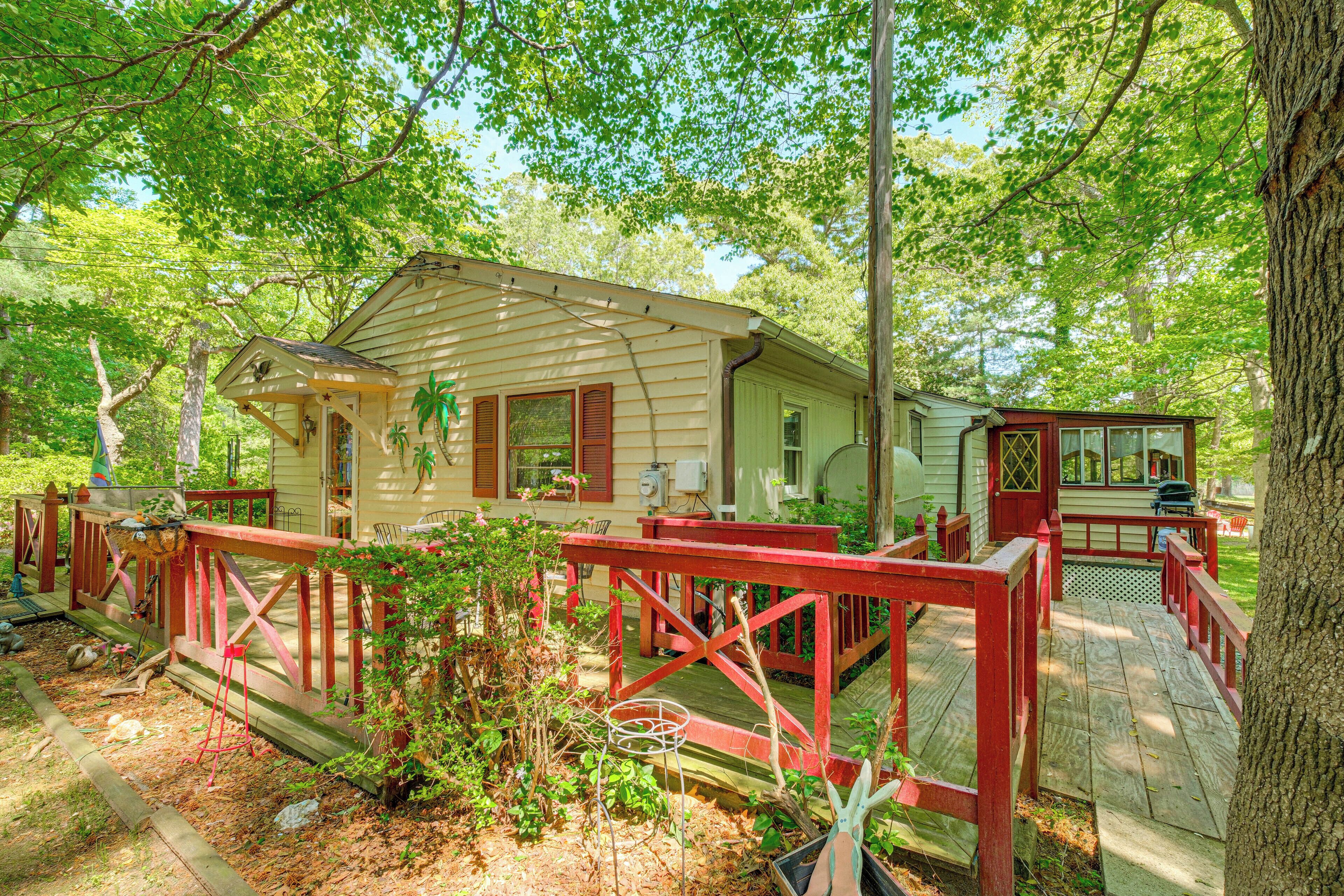 A wooden cabin with a red deck, surrounded by trees.