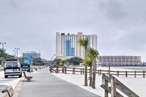 A coastal walkway with a wooden fence, benches, and a clear view of the beach.