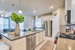 A modern kitchen with stainless steel appliances, a central island, and pendant lighting. - La Porte Getaway w/ Deck: Steps to Beach! (La Porte)