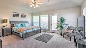 A bedroom with a bed, a ceiling fan, a nightstand, a lamp, a rug, a chair, a TV stand, and a potted plant. - La Porte Getaway w/ Deck: Steps to Beach! (La Porte)