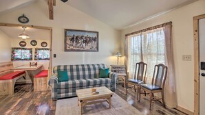 A cozy living room with a plaid sofa, wooden coffee table, and a dining area with a bench. - Kerrville Converted Barn Tiny Home w/ Kayaks! (Kerrville)