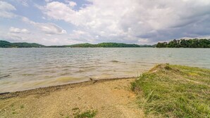 Une vue sur le lac, avec une plage de galets et des zones herbeuses.