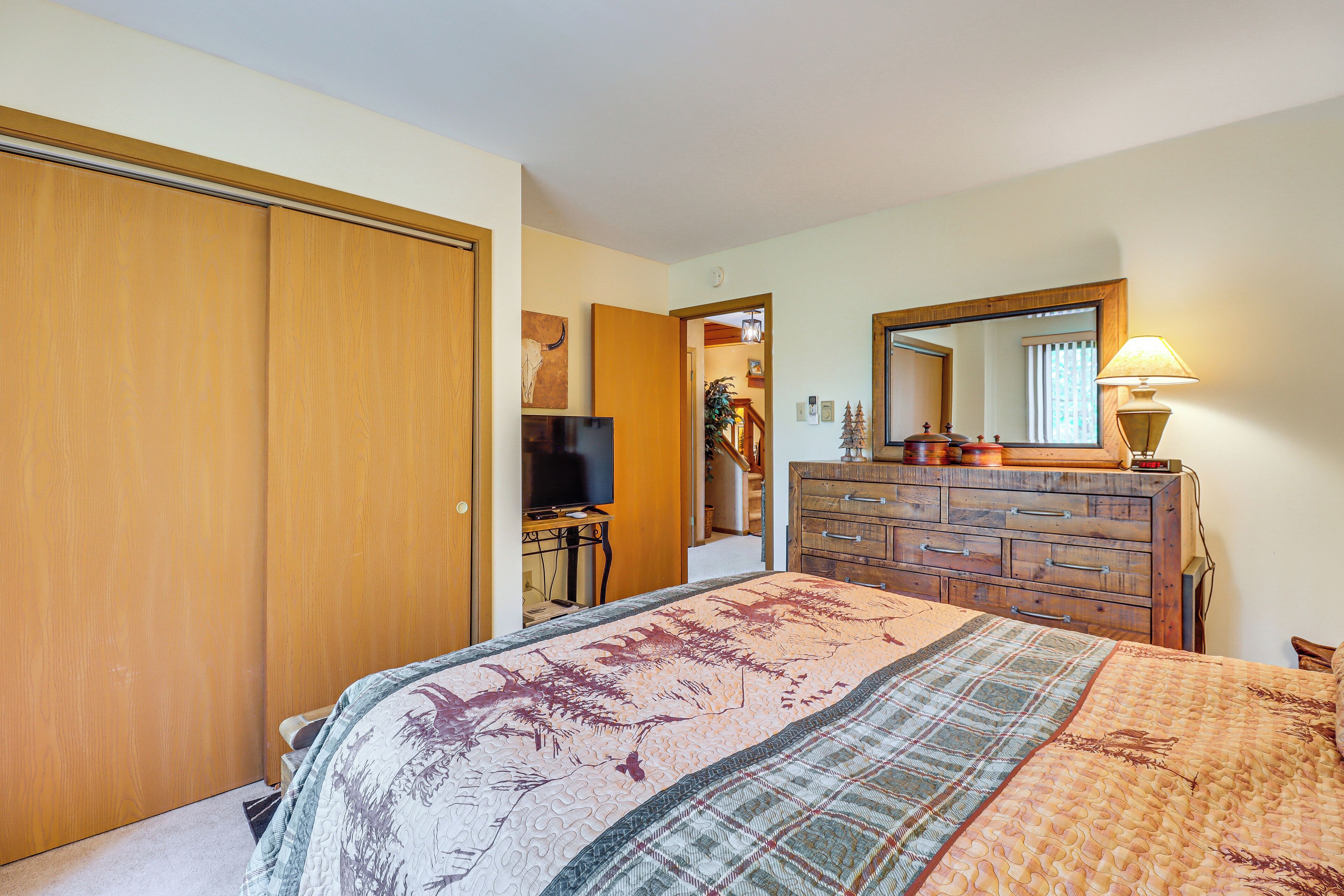 A bedroom with a bed, a dresser, a television, and a mirror.