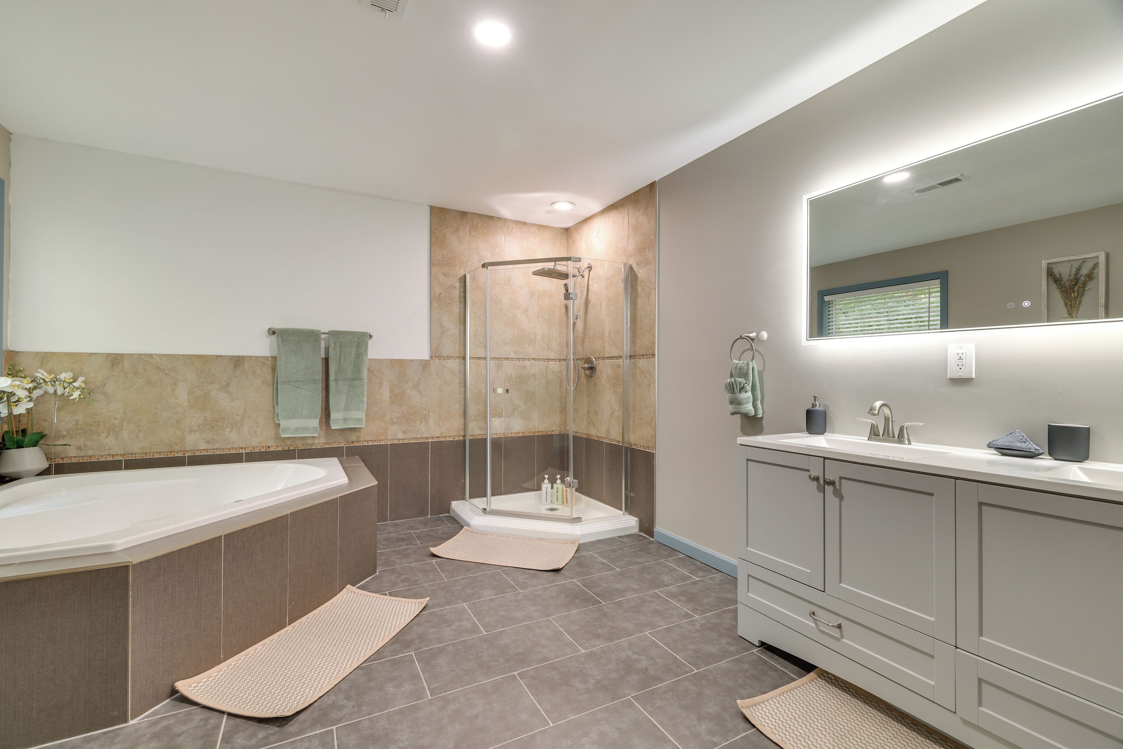 A modern bathroom with a glass-enclosed shower, a large bathtub, and a vanity with a mirror.
