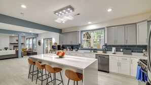 Una cocina moderna con una isla grande, taburetes de bar y una araña.
