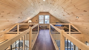 A wooden interior with a central staircase, wooden railings, and a large window at the end. - Inviting Webb Lake Cabin w/ Mountain Views (Weld)