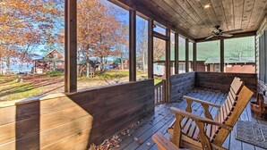 A covered porch with wooden benches, large windows, and a ceiling fan. - Inviting Webb Lake Cabin w/ Mountain Views (Weld)