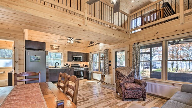 A spacious cabin interior with a dining area, kitchen, and a cozy seating area with a large window offering a view of the outdoors. - Inviting Webb Lake Cabin w/ Mountain Views (Weld)