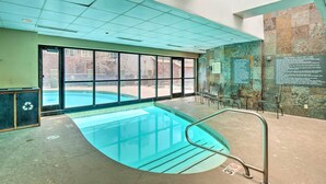 Ein Hallenbad mit klarer Sicht durch große Fenster, einer Metallleiter und einer Wand mit Hinweisschildern.