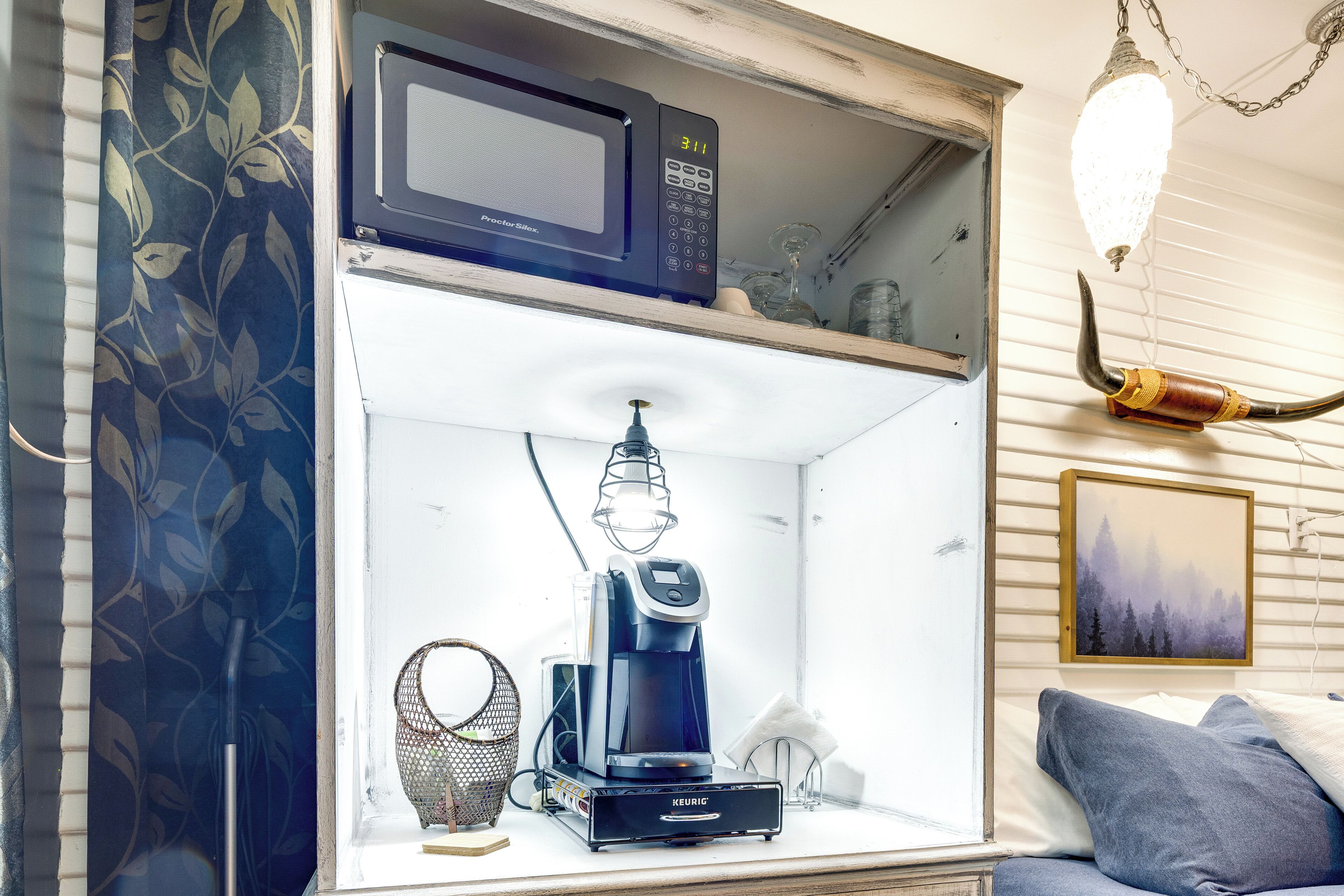 Una kitchenette equipada con microondas, cafetera y una lámpara colgante.