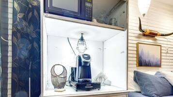 Una kitchenette equipada con microondas, cafetera y una lámpara colgante.