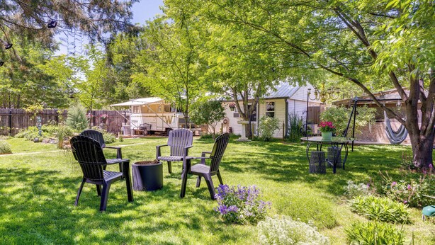 Un jardin avec une terrasse, des chaises et un hamac.