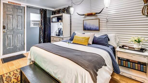 A bedroom with a bed, a nightstand, a dresser, and a door with a sign. - Las Animas Studio w/ Lush Backyard Paradise! (Las Animas)