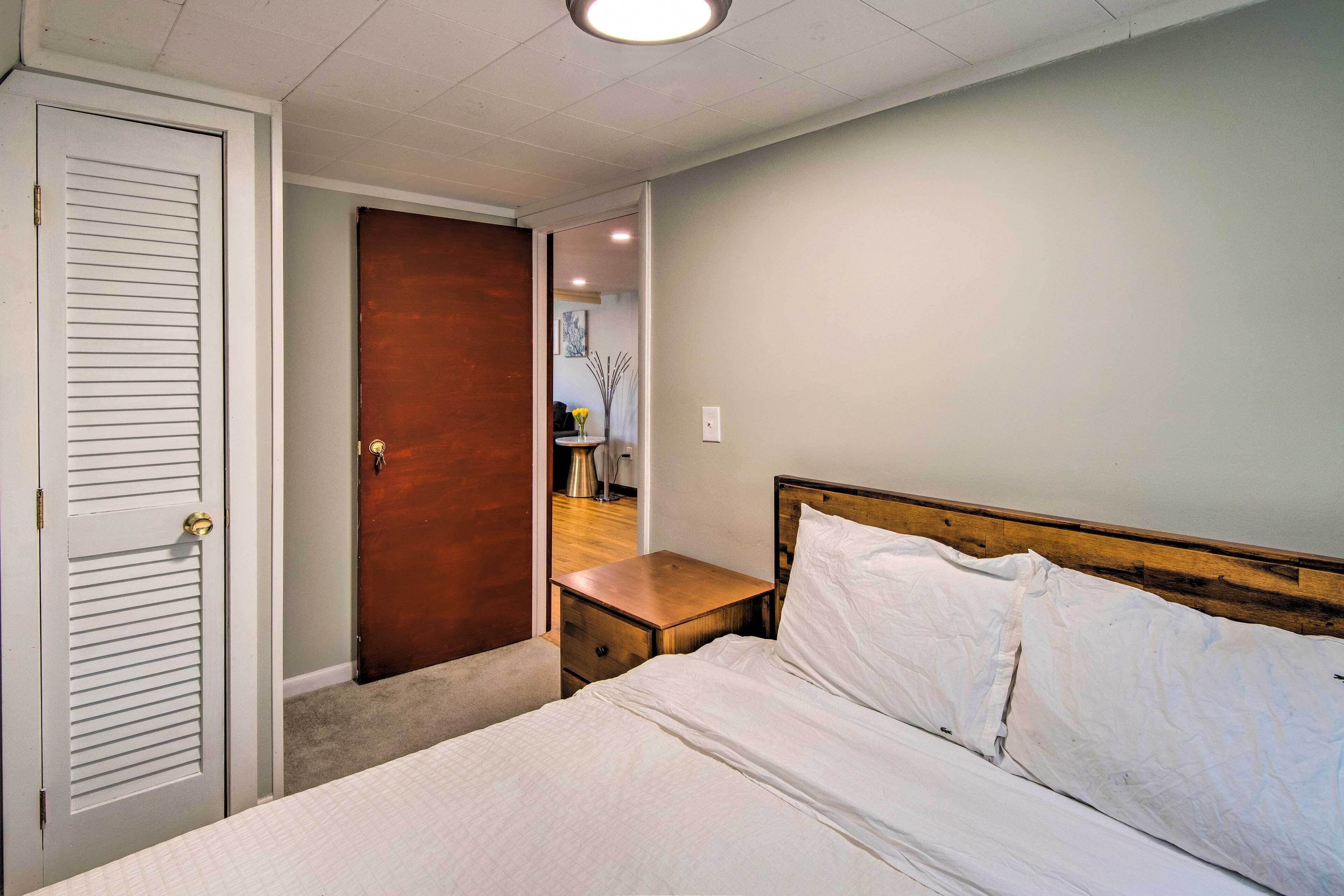A bedroom with a bed, a wooden nightstand, a white door, and a wooden wall.