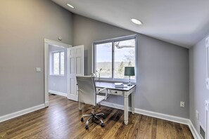 Una habitación con escritorio, silla y ventana grande.