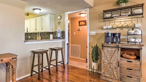 A kitchen with wooden stools, a coffee station, and a rustic cabinet with drawers. - Lakefront Home w/ Point Venture Golf Access! (Leander)