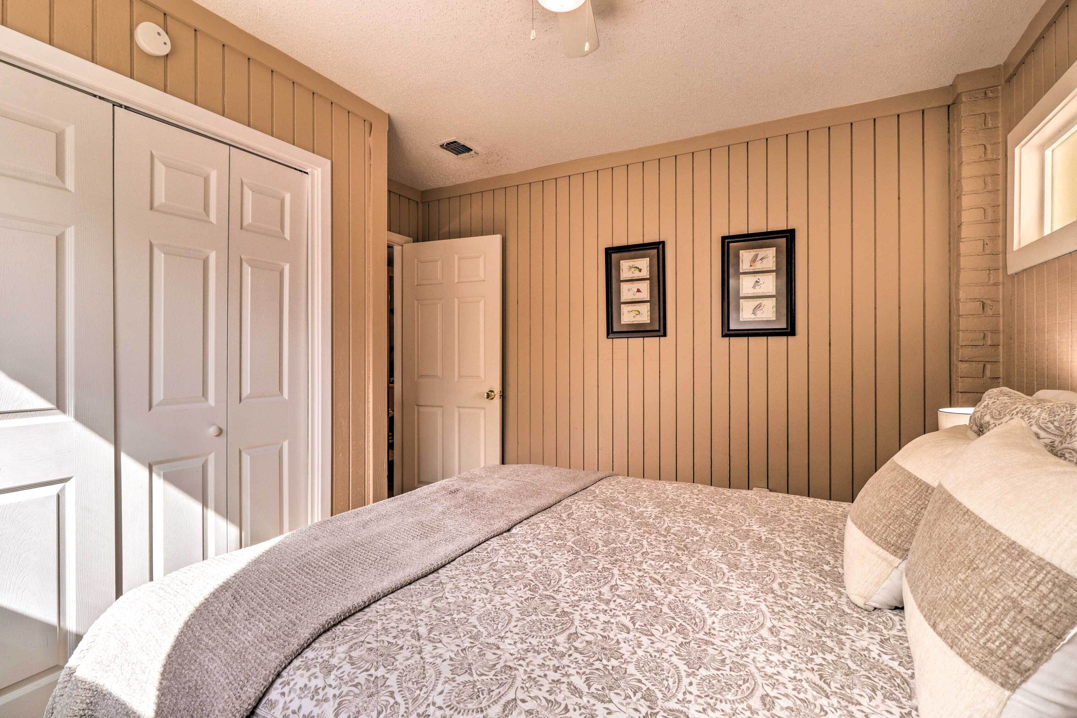A bedroom with a bed, a door, and two framed pictures on the wall.