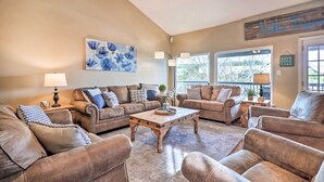 A living room with leather sofas, a coffee table, and a painting on the wall. - Lakefront Home w/ Point Venture Golf Access! (Leander)