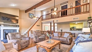 A spacious living room with leather sofas, a wooden coffee table, and a staircase leading to an upper level. - Lakefront Home w/ Point Venture Golf Access! (Leander)