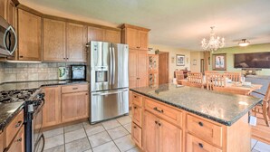 A kitchen with wooden cabinets, a stainless steel refrigerator, a granite countertop, and a chandelier. - Hugo Home, Direct Lake Access & Private Dock! (Hugo)