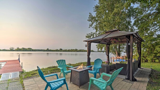 A patio with outdoor seating and a fire pit by a lake. - Hugo Home, Direct Lake Access & Private Dock! (Hugo)