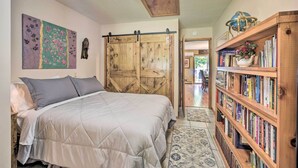 A bedroom with a bed, a wooden wardrobe, a bookshelf, and a painting on the wall. - Hugo Home, Direct Lake Access & Private Dock! (Hugo)