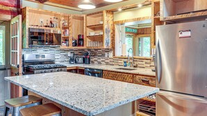 Eine moderne Küche mit Granit Arbeitsplatten, Edelstahlgeräten und Holzschränken.