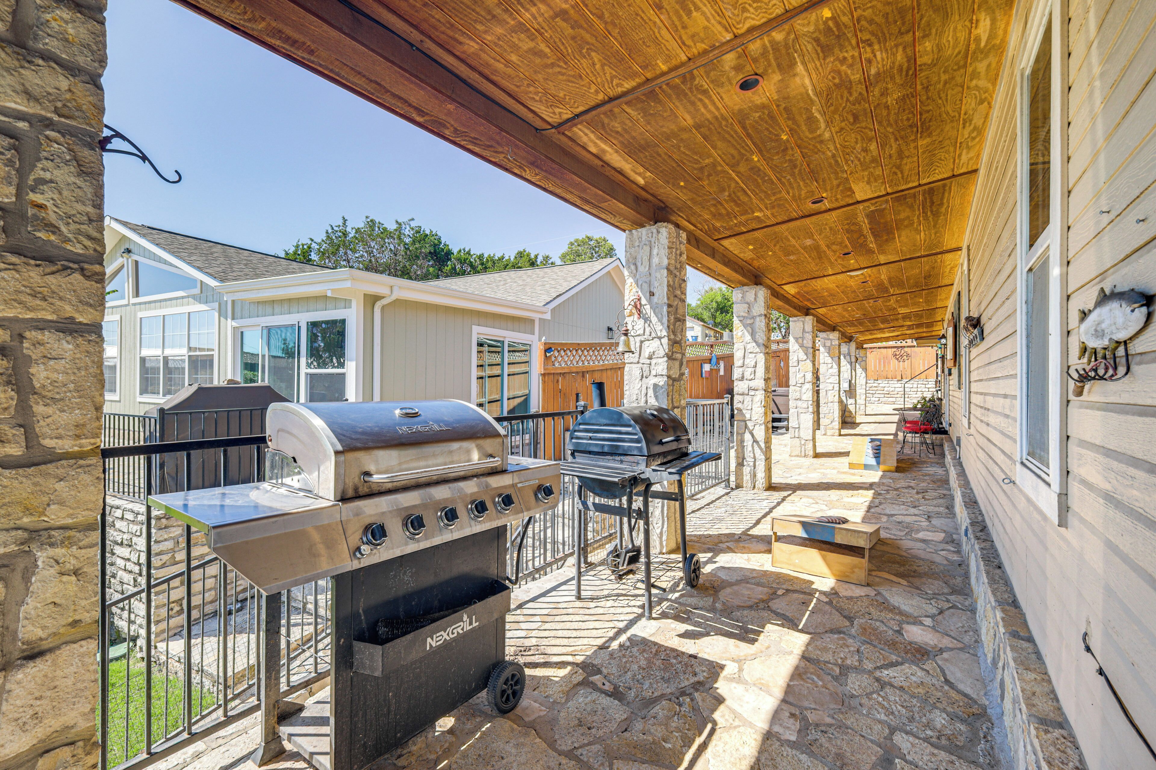 A covered patio area with a stone floor, a grill station, and a seating area with a table and chairs.
