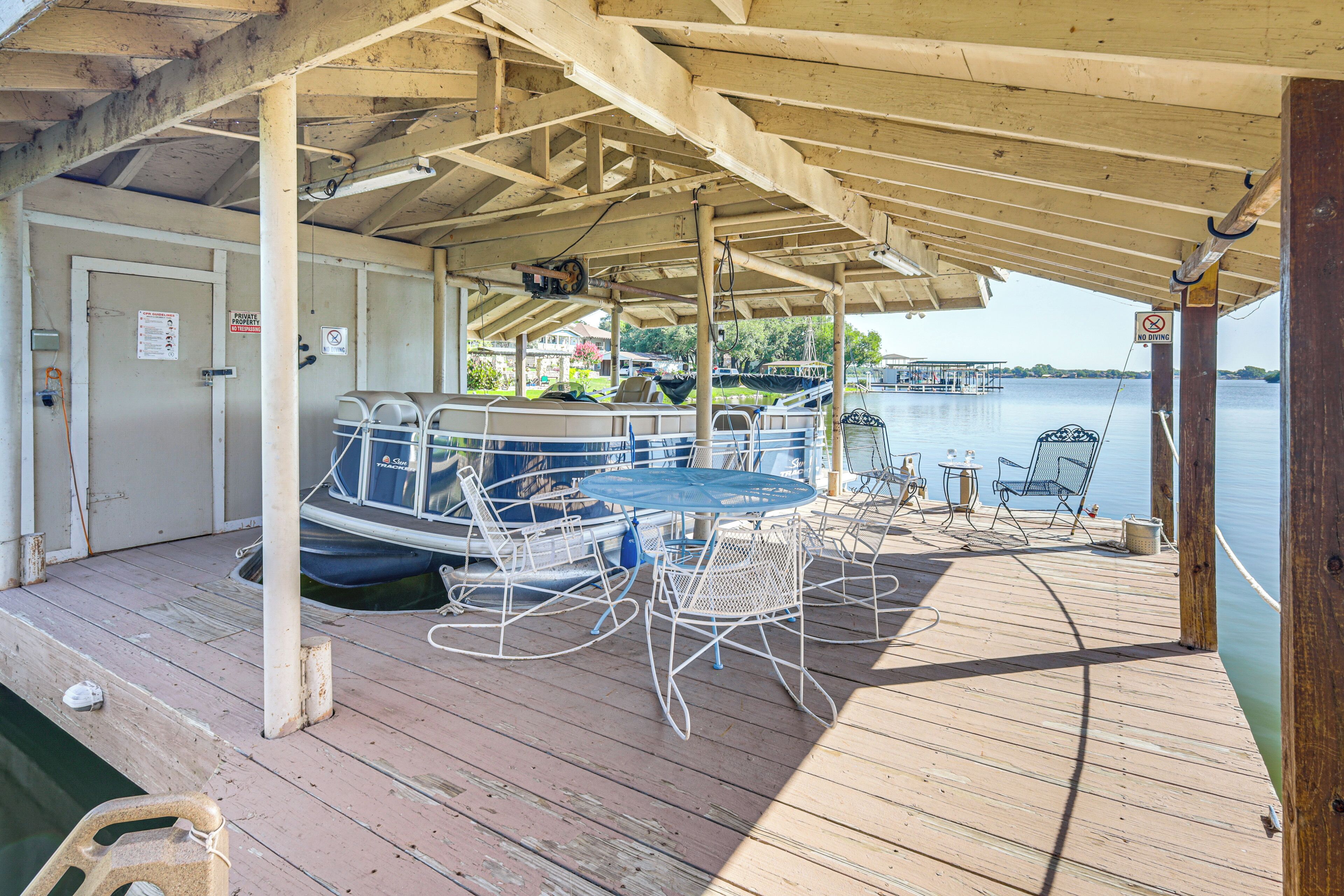 A covered dock area with a boat, seating, and a view of the water.