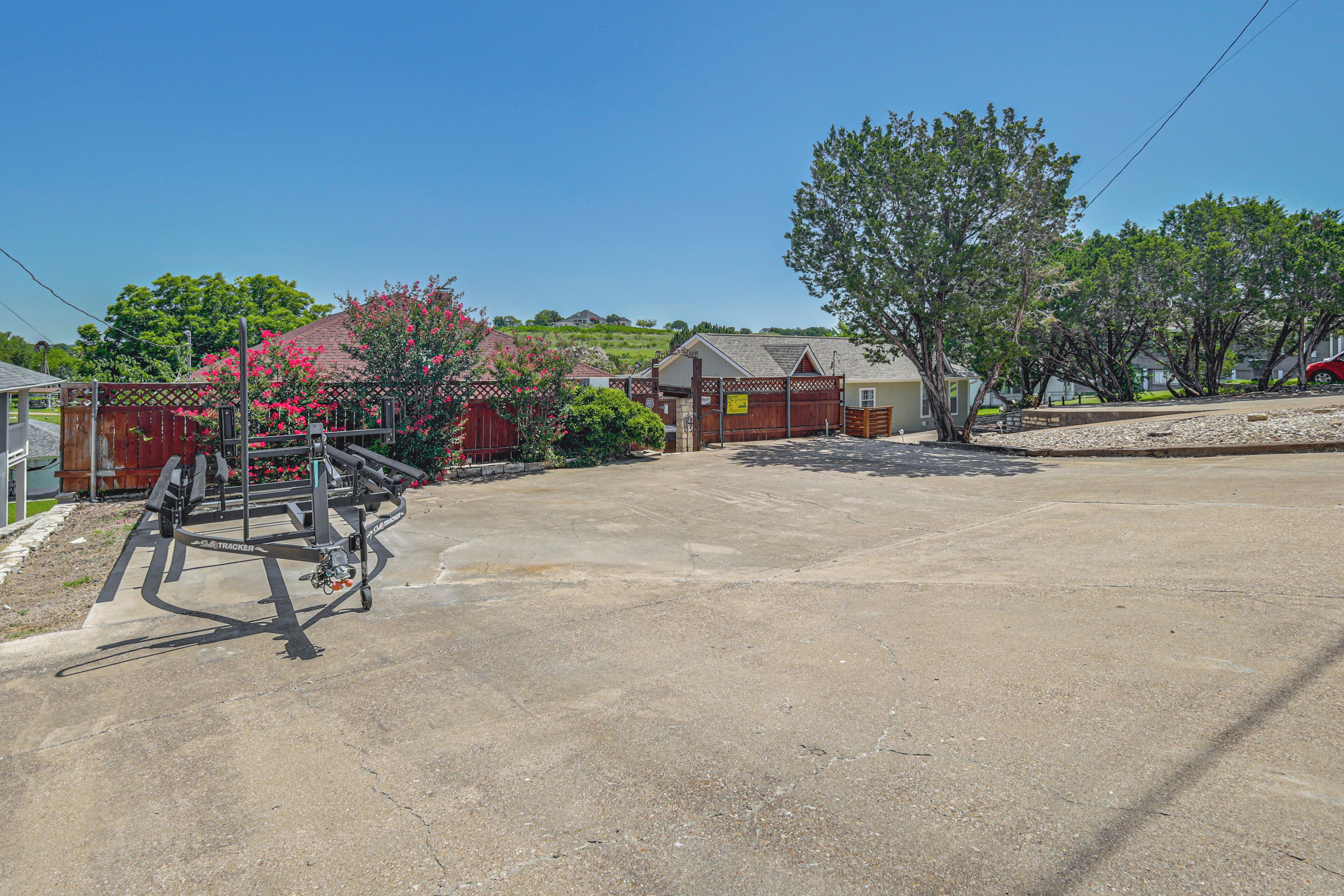 A residential driveway with a concrete surface, a wooden fence, and a red car parked on the right.