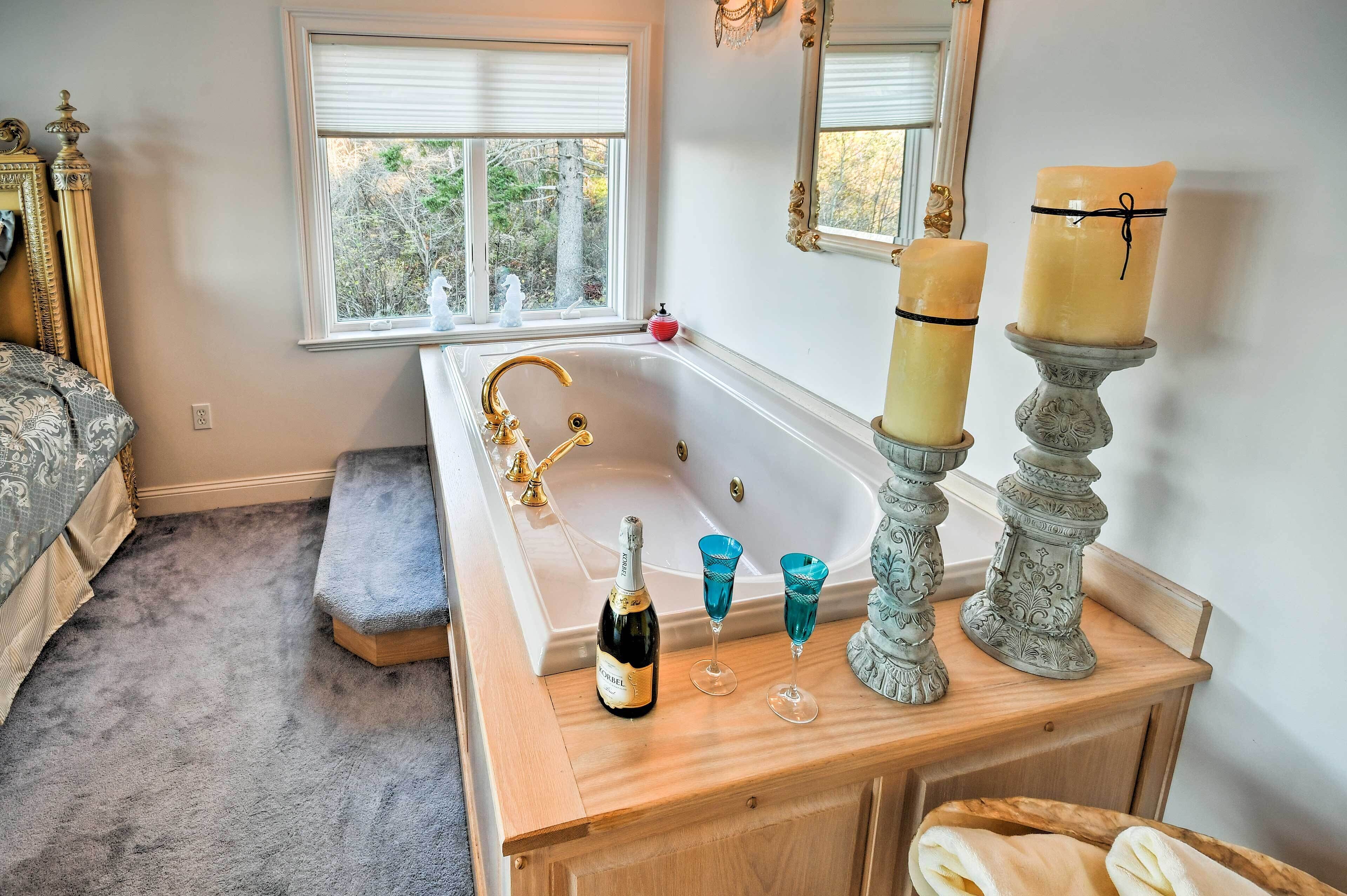 A bathroom with a bathtub, a wooden vanity, a bottle of champagne, and two candles.