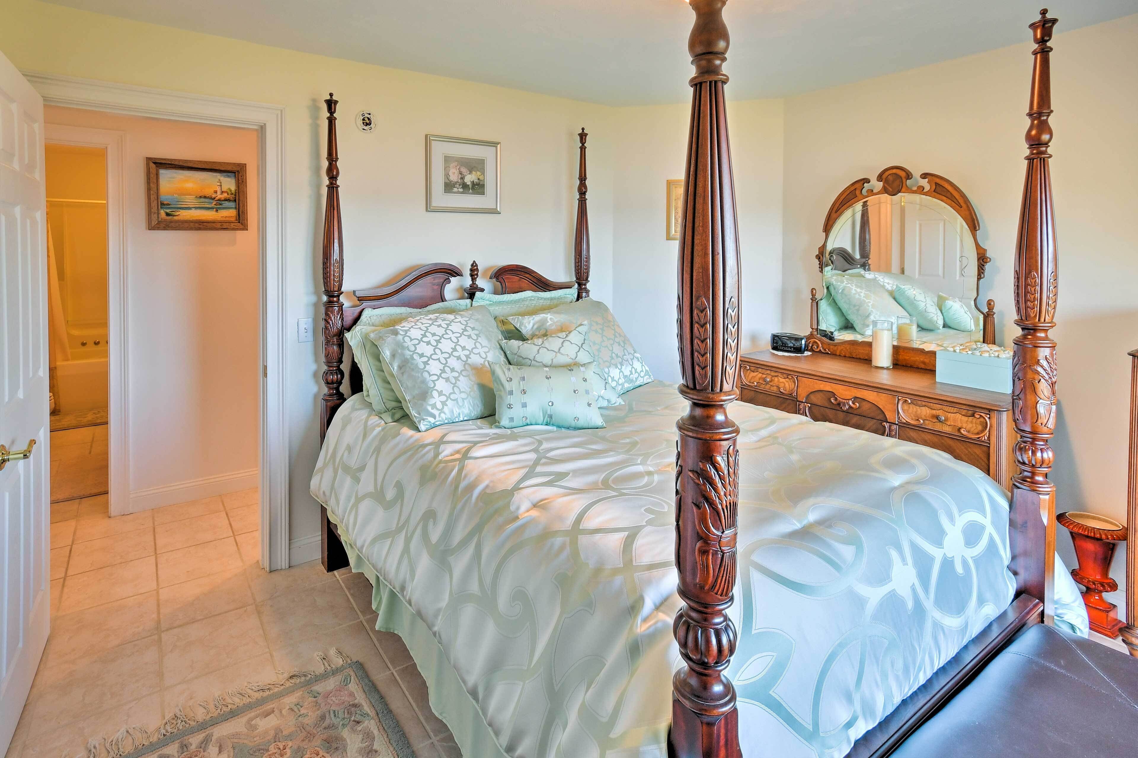 A four-poster bed with a wooden headboard, a bedside table with a candle, and a mirror above the bed.