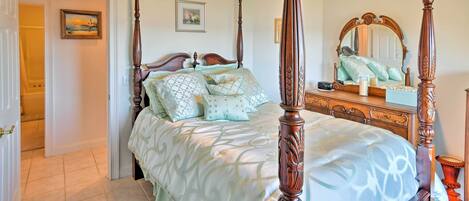A four-poster bed with a wooden headboard, a bedside table with a candle, and a mirror above the bed.