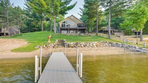 Une propriété au bord du lac, dotée d’un quai menant à une maison entourée d’arbres.