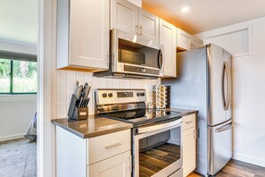 A modern kitchen with stainless steel appliances, white cabinetry, and a window providing natural light.